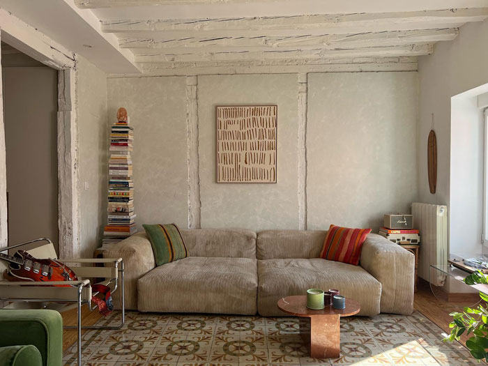 Living space with big beige colored couch and a painting in the middle of the wall