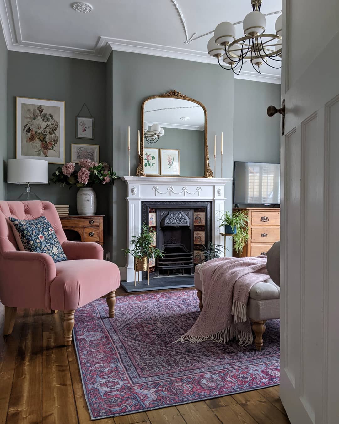 Traditional style living room with pink armchair and fireplace with a mirror above it