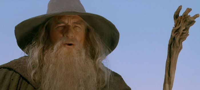 Gandalf speaking with a staff in his hand