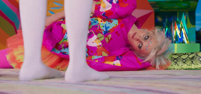 Weird Barbie lying on the floor in a colorful dress, with white legs standing nearby. Weird Barbie lying on the floor in a colorful dress, with white legs standing nearby.