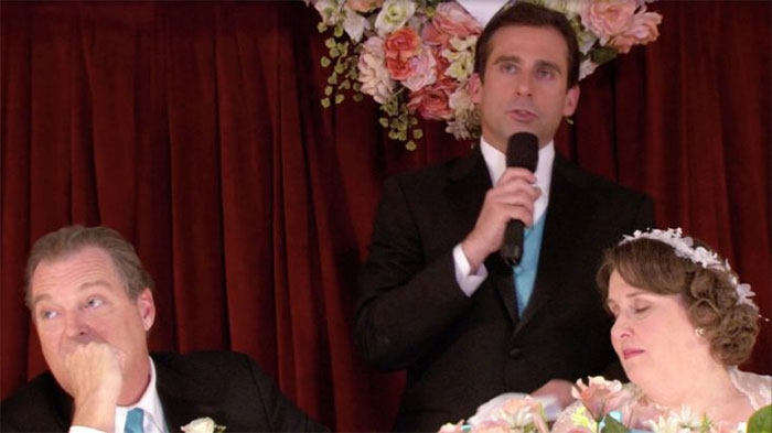 Michael Scott speaks through the microphone at the wedding