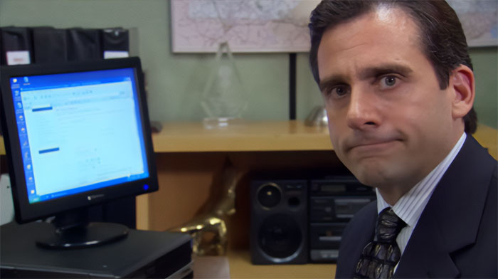 Michael Scott is sitting at the computer