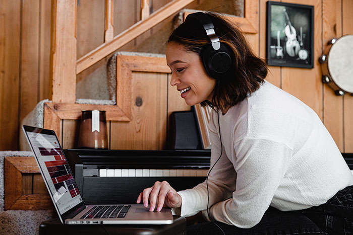 Woman creating music with laptop and smiling