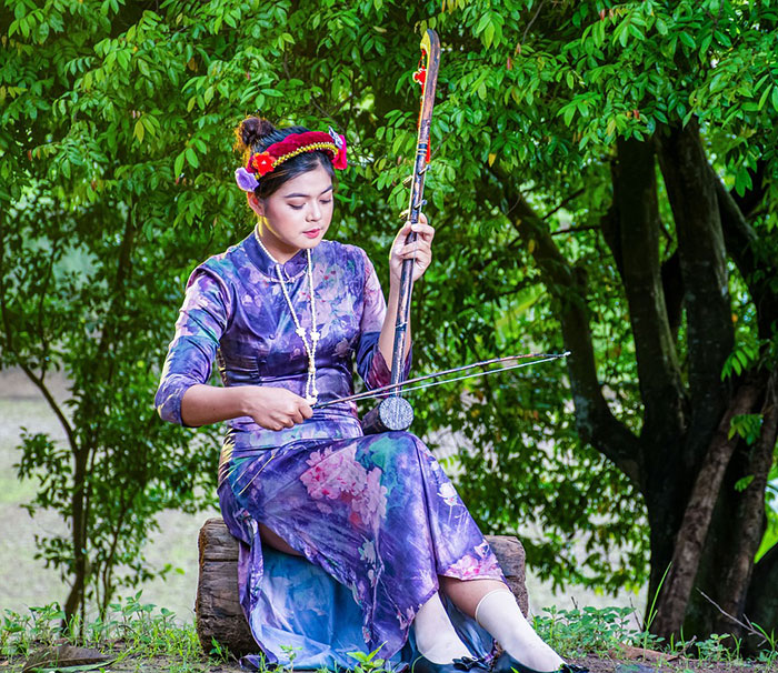 Woman wearing flower dress playing with erhu instrument