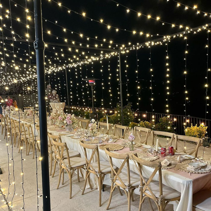 Outdoor light canopy with tables with white sheets and wooden chairs