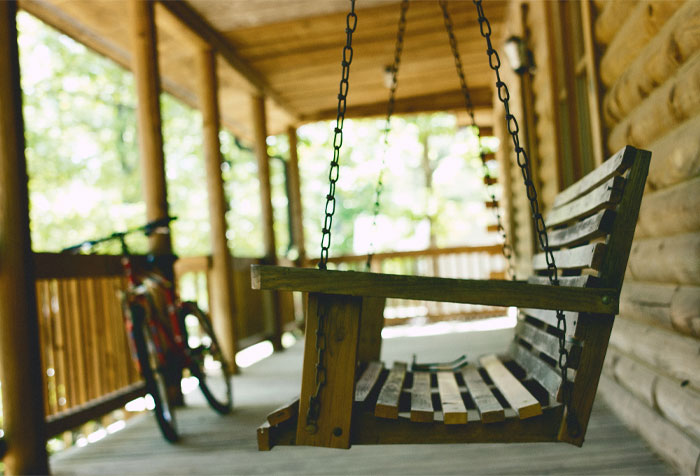 A brown wooden bench porch swing with a cycle in the background