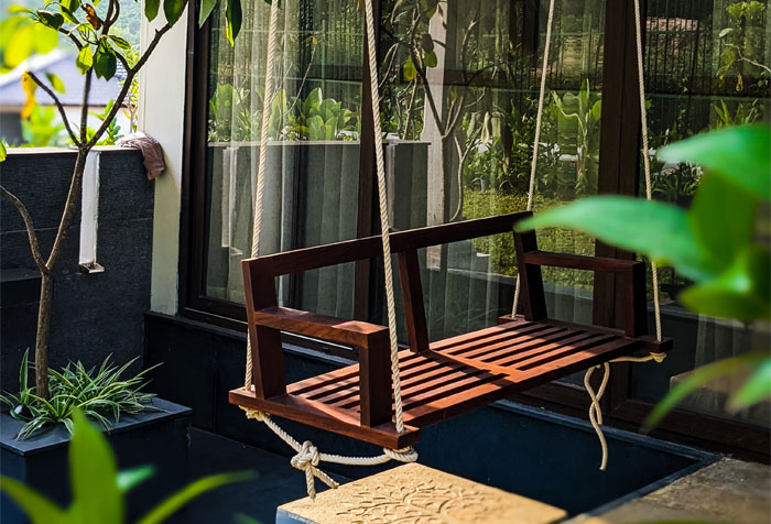 A rope-based farmhouse porch swing surrounded by plants A rope-based farmhouse porch swing surrounded by plants