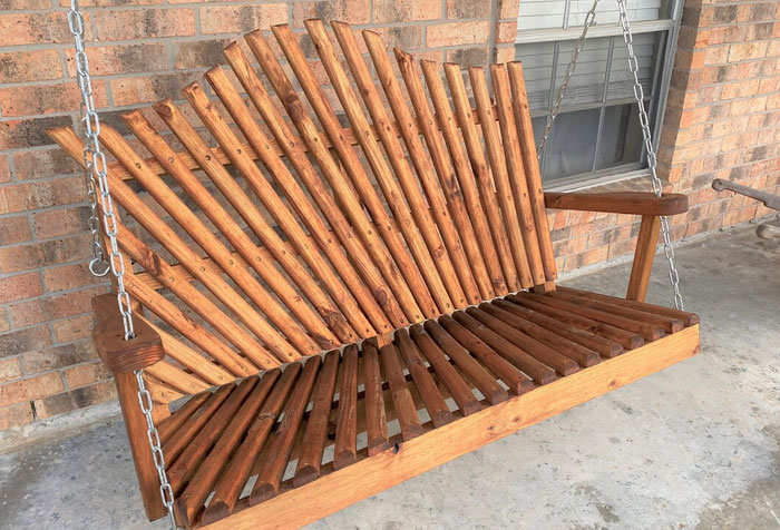 A chain-based brown wooden handcrafted highback porch swing A chain-based brown wooden handcrafted highback porch swing