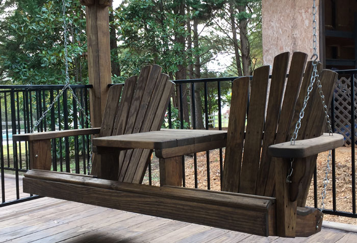 A chain-based brown wooden Adirondack porch swing A chain-based brown wooden Adirondack porch swing