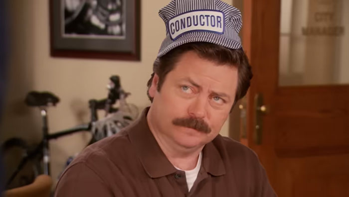 Ron Swanson with a blue 'Conductor' hat on his head