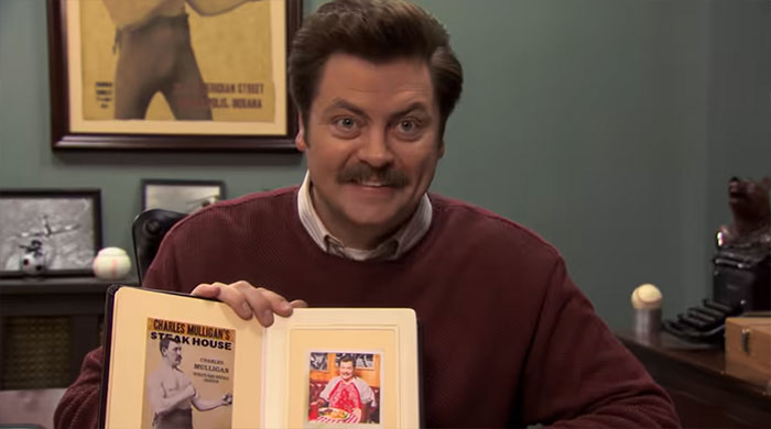 Ron Swanson smiling and showing a book