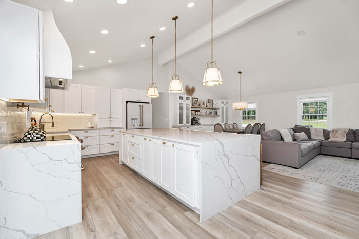 a large kitchen with a center kitchen island and white marble counter tops