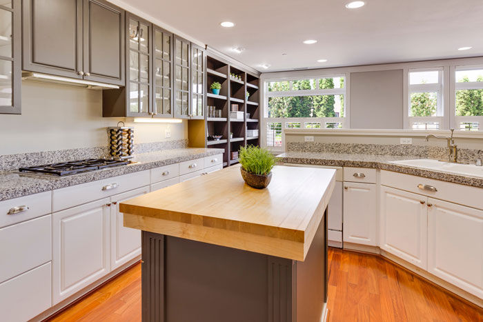 white and gray kitchen with butcher block kitchen island in the middle