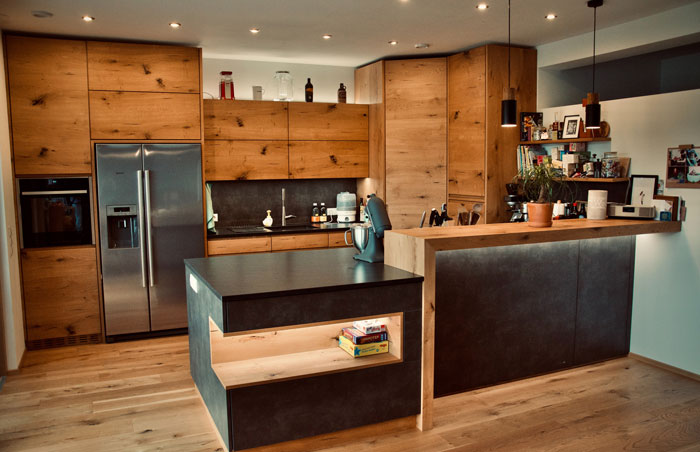 a kitchen with wooden cabinets, irregular kitchen island and a stainless steel refrigerator