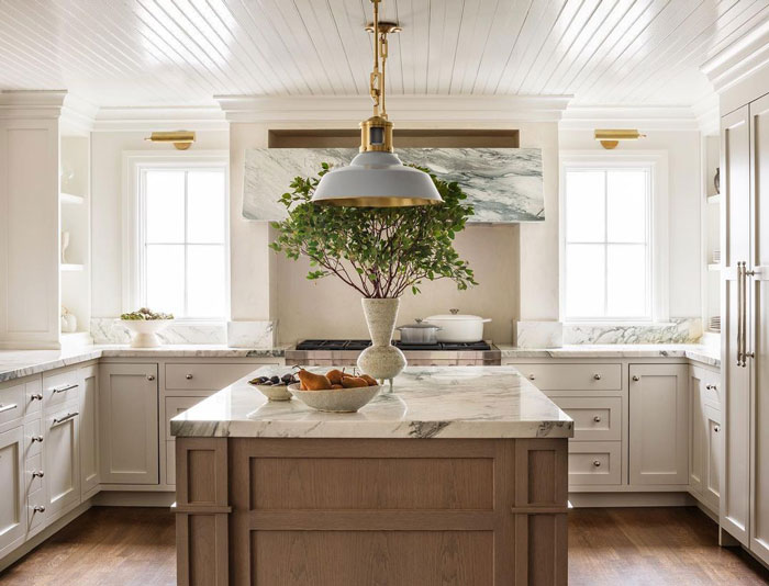 wooden kitchen island with marble countertop and fruits with vase on it
