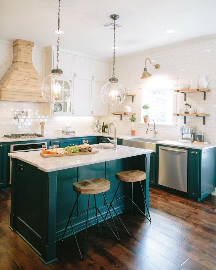 a kitchen with a dark green kitchen island with bar chairs