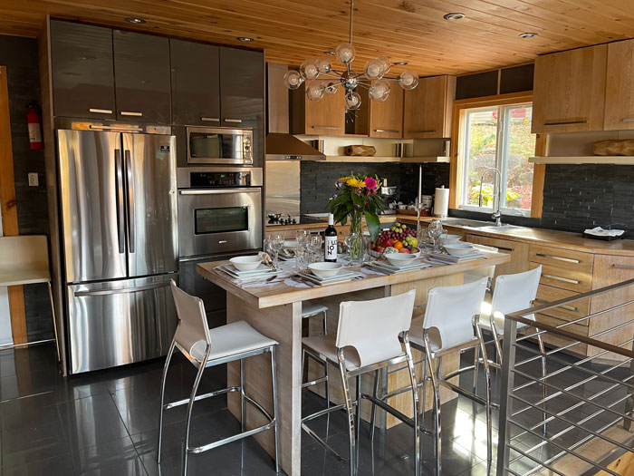 a kitchen with stainless steel appliances and a kitchen island with white bar chairs 