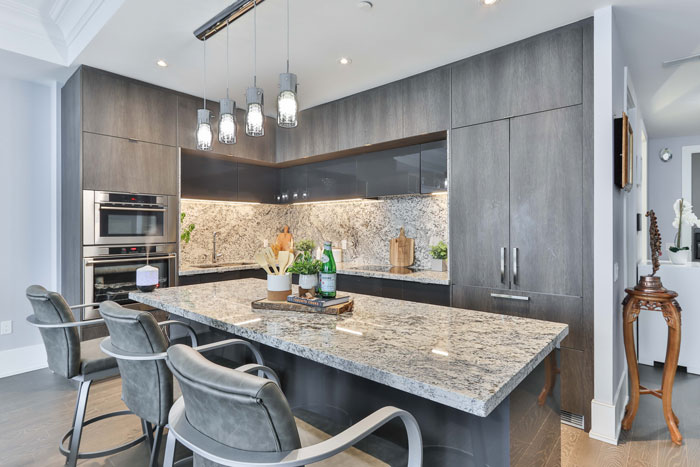 granite material kitchen island with gray chairs beside