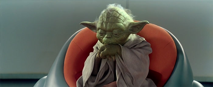 Yoda sitting on a red coach and looking thoughtful