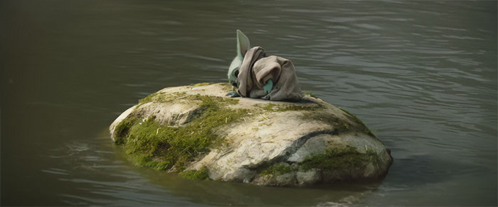 Yoda lying down on a stone in the middle of the lake