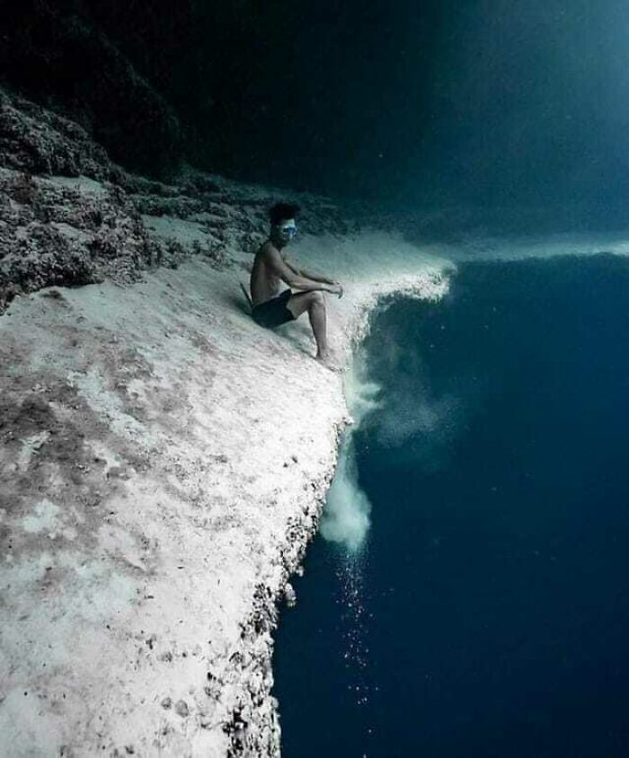 Diver Sitting On The Edge Of Underwater Sea Cliff