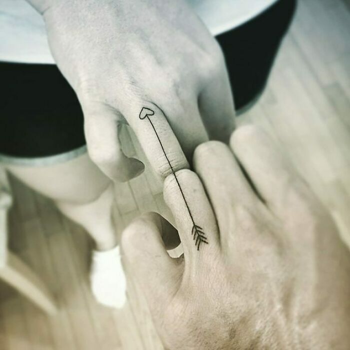 Matching arrows that line up finger tattoo