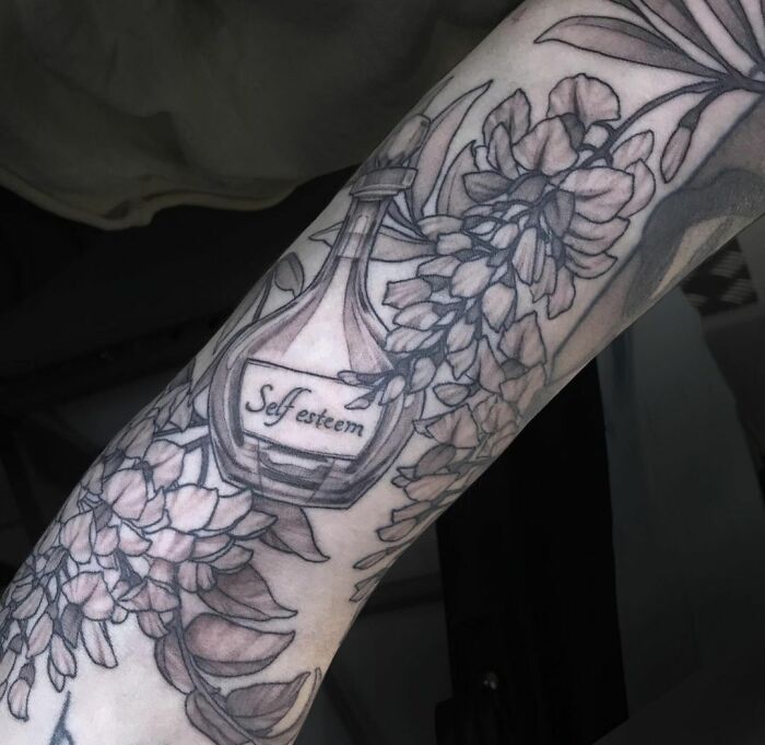 Flowers with bottle of self esteem arm sleeve tattoo