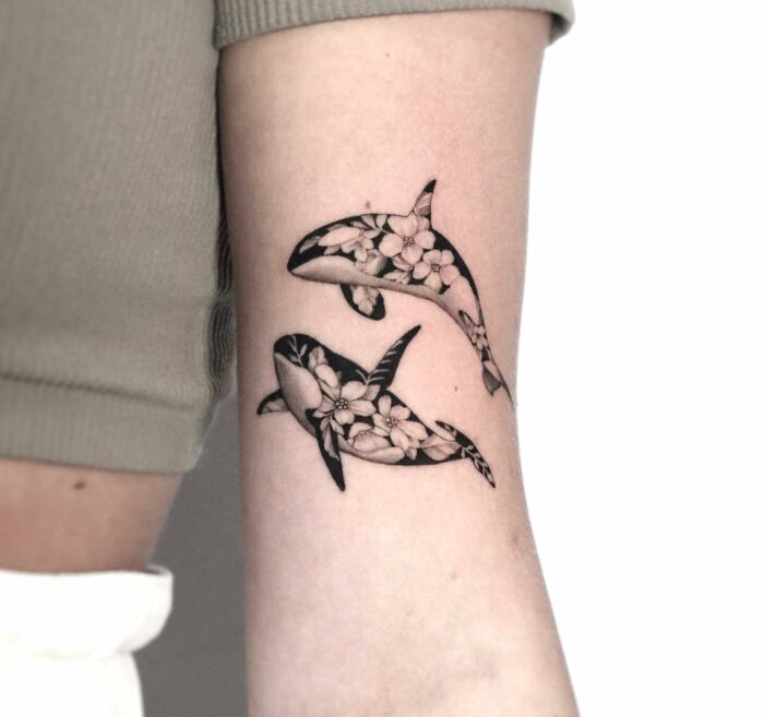Orca family with flowers arm tattoo
