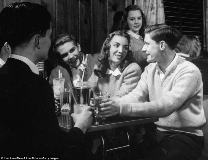 1944 - Flirting: A Young Women Flaunts Her Charm While Sipping A Milkshake With Some Teenage Boys