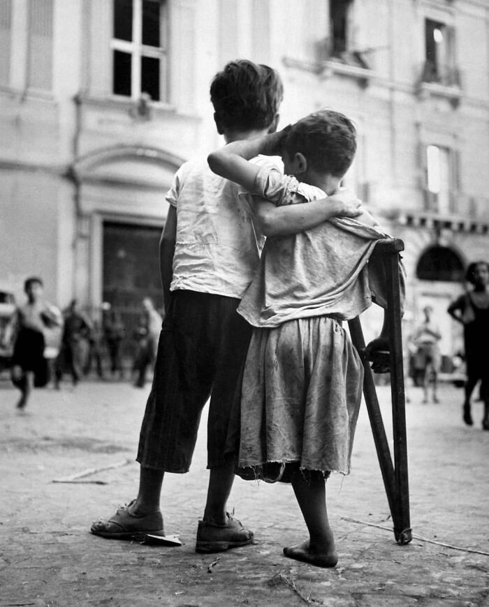 An Italian Boy Helps His Little Brother Who Lost His Leg During The Bombing Of Naples. 1944