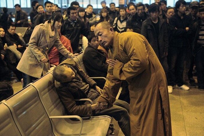 Monje budista rezando mientras sostiene la mano de un hombre que murió en una estación de tren en China. 2011