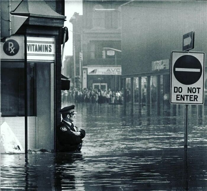 Canadian Police Officer Guarding The Pharmacy In Waist-High Flood Waters In Galt, Ontario, 1974