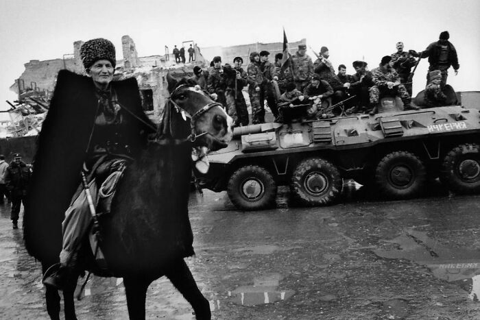 An Elderly Chechen Man Wearing Traditional Clothes, Poses On A Horse While Chechen Rebels Behind Him Stand On Top Of A Captured Russian Armored Vehicle, Grozny, Chechnya, First Chechen War(1994-1996