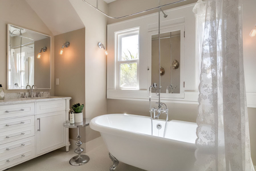 Double slipper clawfoot tub with shower and white curtains.