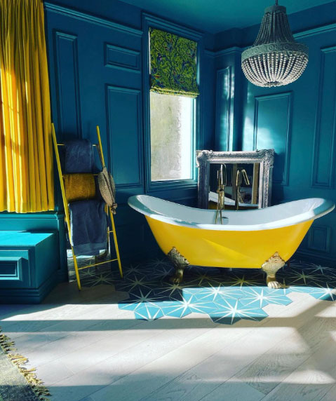 Yellow double ended clawfoot tub in colorful room.