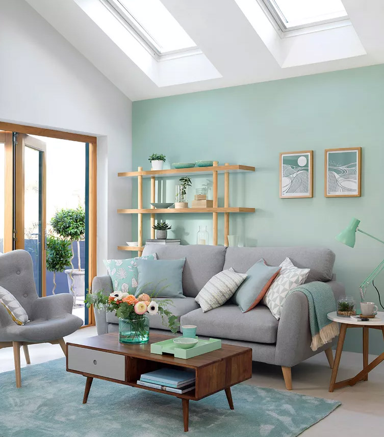 Interior with mint green walls, brown wooden furniture, and gray sofa