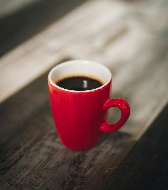 A red cup of coffee on a wooden table