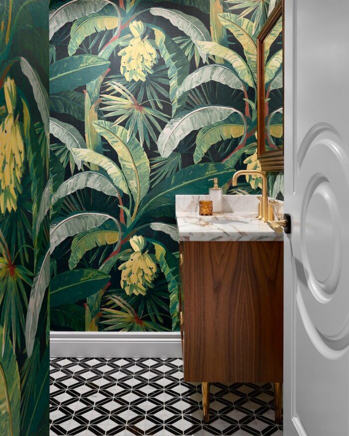 Bathroom with tropical leaves wallpaper, brown wooden vanity, marble countertop, and geometric black and white floor tiles. Bathroom with tropical leaves wallpaper, brown wooden vanity, marble countertop, and geometric black and white floor tiles.