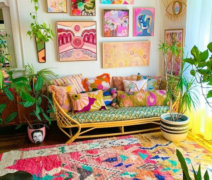 a colorful maximalist living room with many plants, a patterned rug, a bright sofa, and paintings on the wall