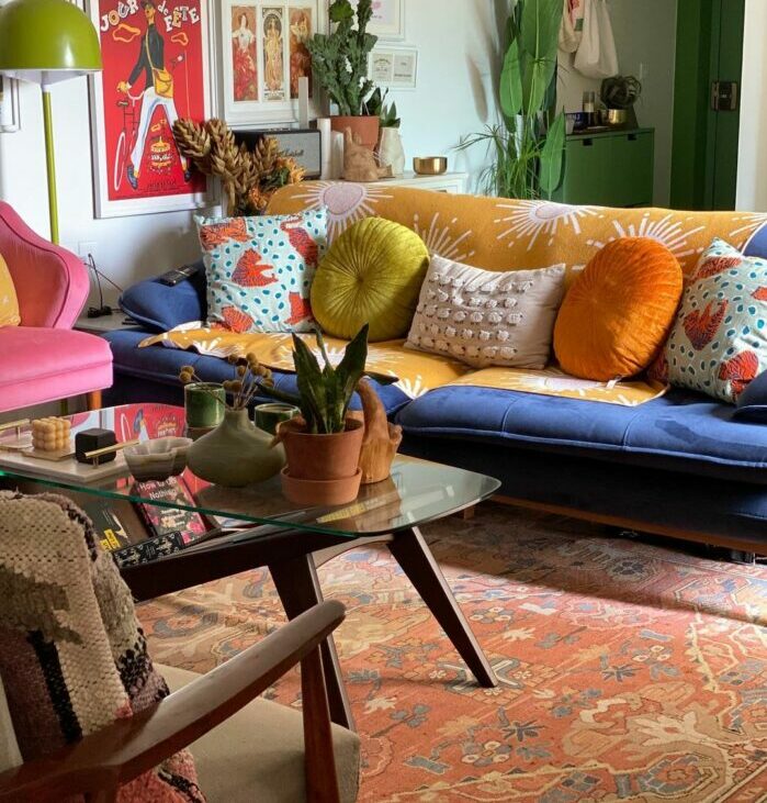 a maximalist living room with a blue sofa and many colorful pillows
