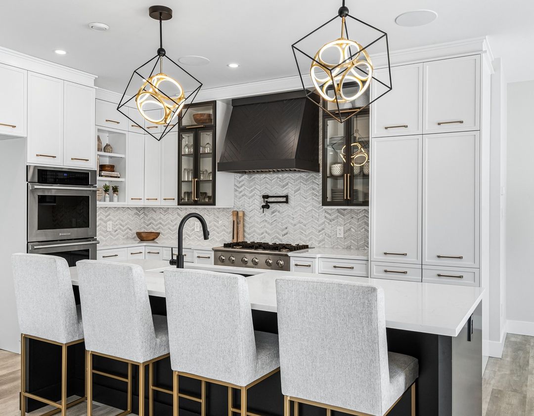 White kitchen with white marble table chairs and artful lights