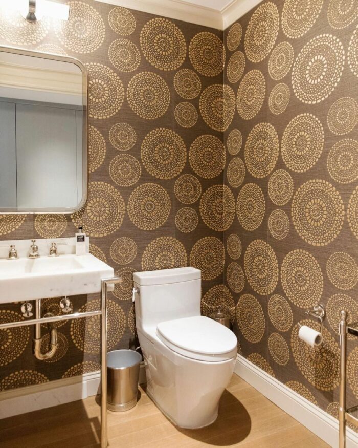 Bathroom with brown circle-pattern wallpaper with toilet and sink