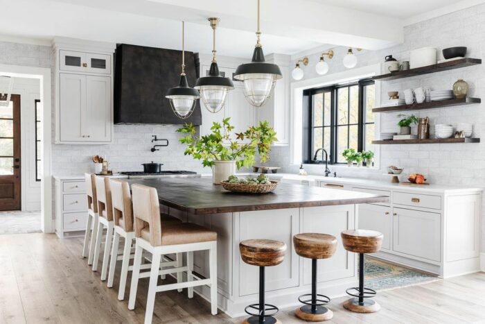 White kitchen with marble table wooden chairs and lights