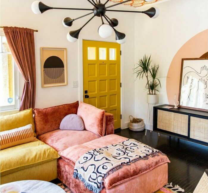 a maximalist living room with a pink and yellow sofa and orange wallpaper on the ceiling