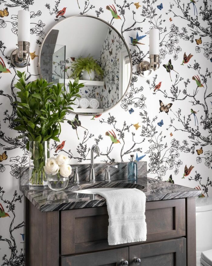 Bathroom with branches birds and butterflies wallpaper and brown cupboard with marble sink