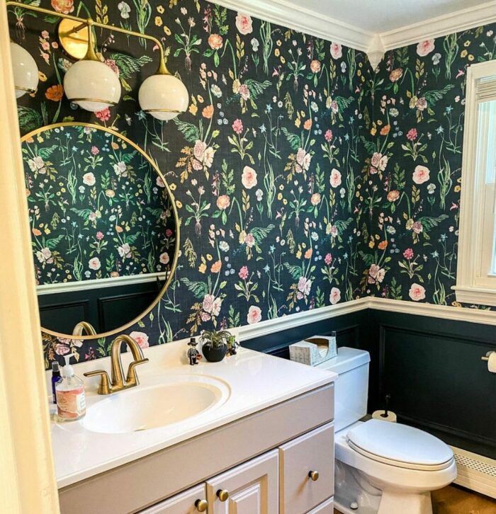 Bathroom with black flower wallpaper and gray cupboard with sink and toilet