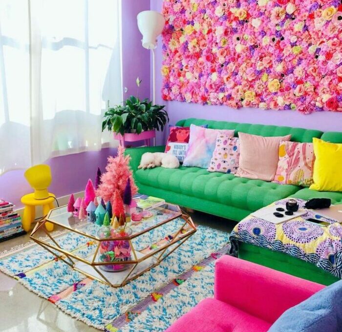 a maximalist living room with a flower wall, a green sofa, and many colorful items