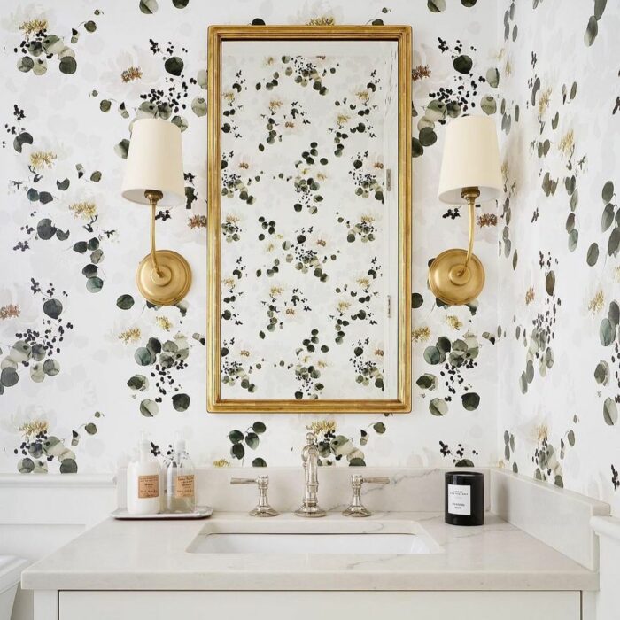 Bathroom with minimalist floral wallpaper, marble sink, gold-framed mirror, and brass wall sconces showcasing trendy bathroom wallpaper ideas. Bathroom with minimalist floral wallpaper, marble sink, gold-framed mirror, and brass wall sconces showcasing trendy bathroom wallpaper ideas.