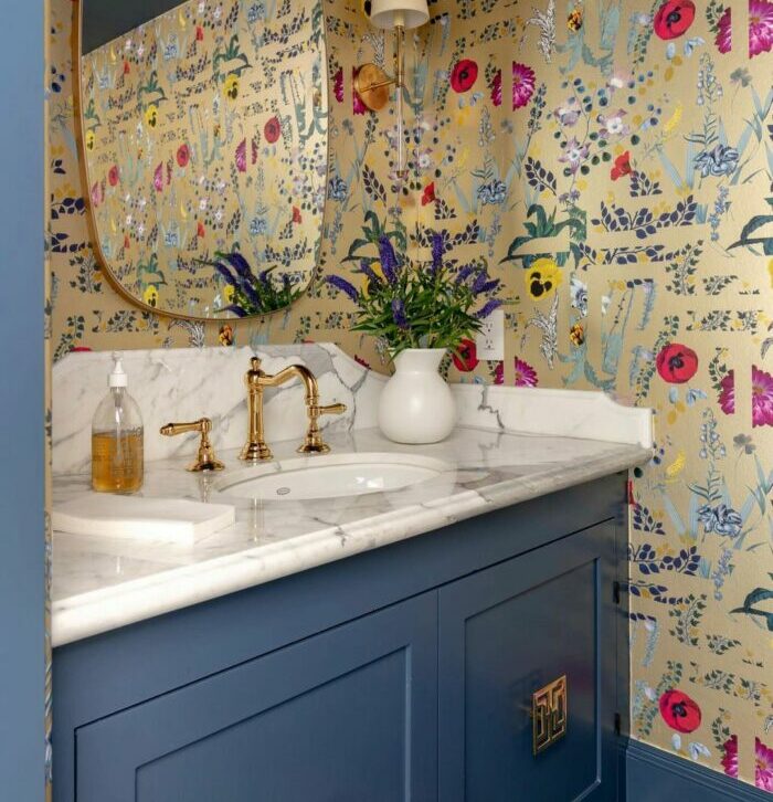 Bathroom with colorful flower wallpaper and contrasting blue cupboard with marble sink
