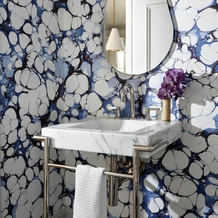 Bathroom with trendy blue cloud wallpaper and a marble sink featuring modern fixtures and a small mirror. Bathroom with trendy blue cloud wallpaper and a marble sink featuring modern fixtures and a small mirror.